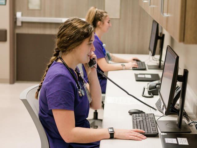 穿着紫色工作服的学生在电脑前工作